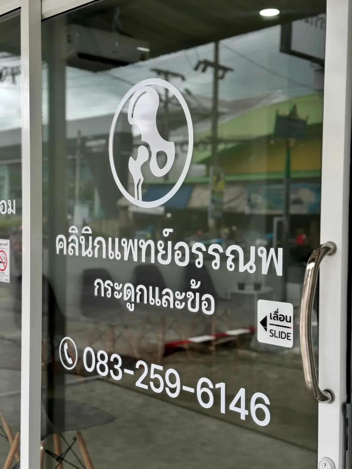 ทางเข้าคลินิกกระดูกและข้อแพทย์อรรณพ พร้อมโลโก้คลินิกบนประตูกระจก